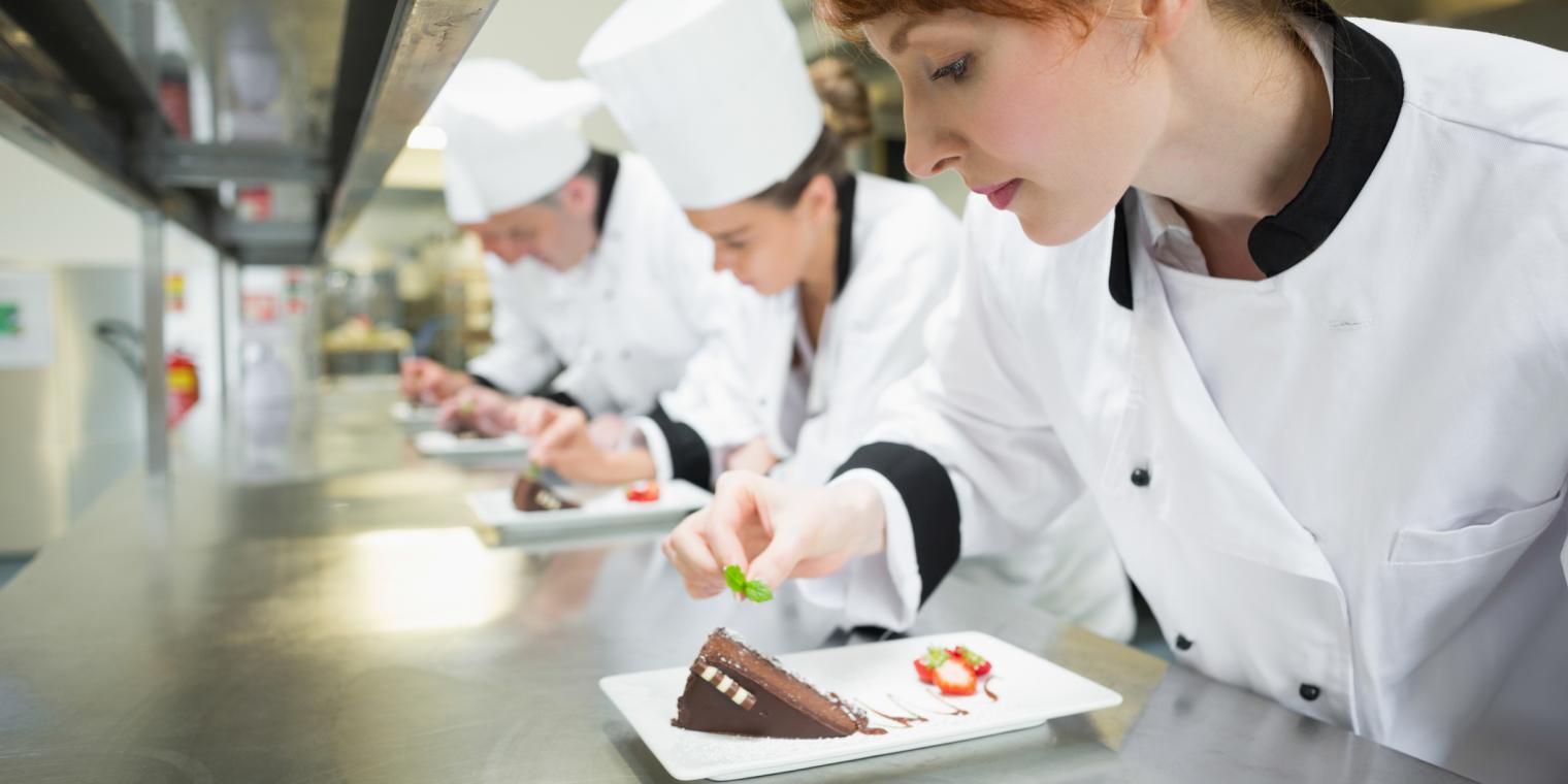 a group of chef preparing desert on a plate